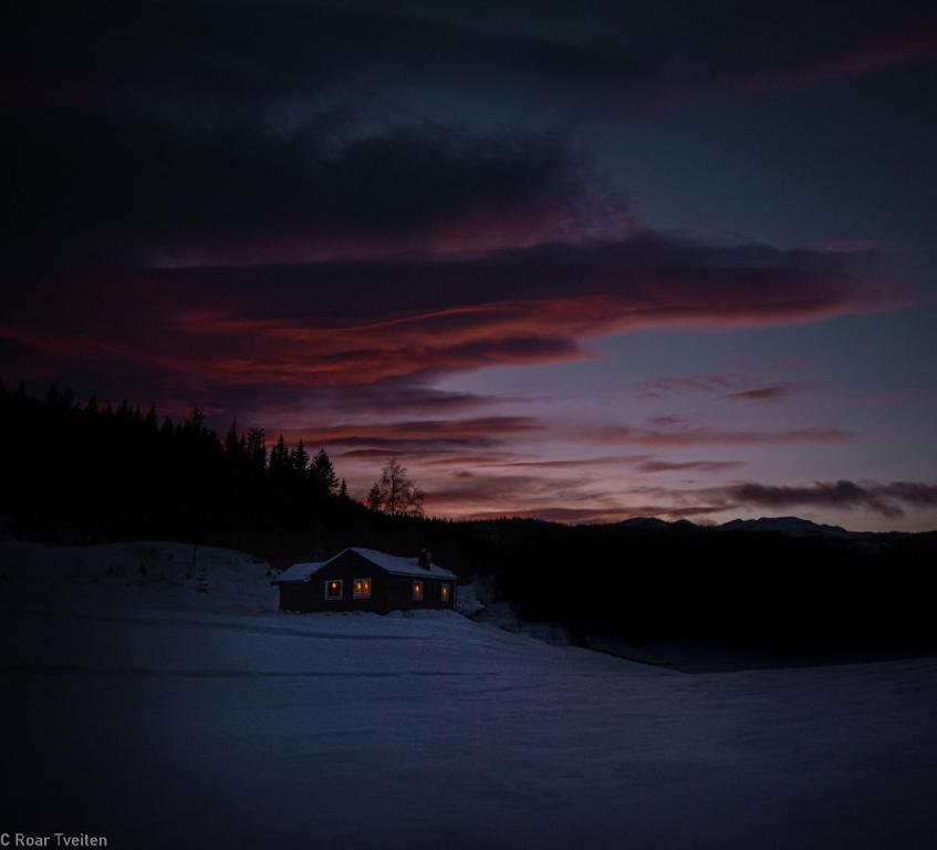 TuddalTuddal Hyttegrend, GAMLESTUGU, Telemark的雪中的房子,背景是日落