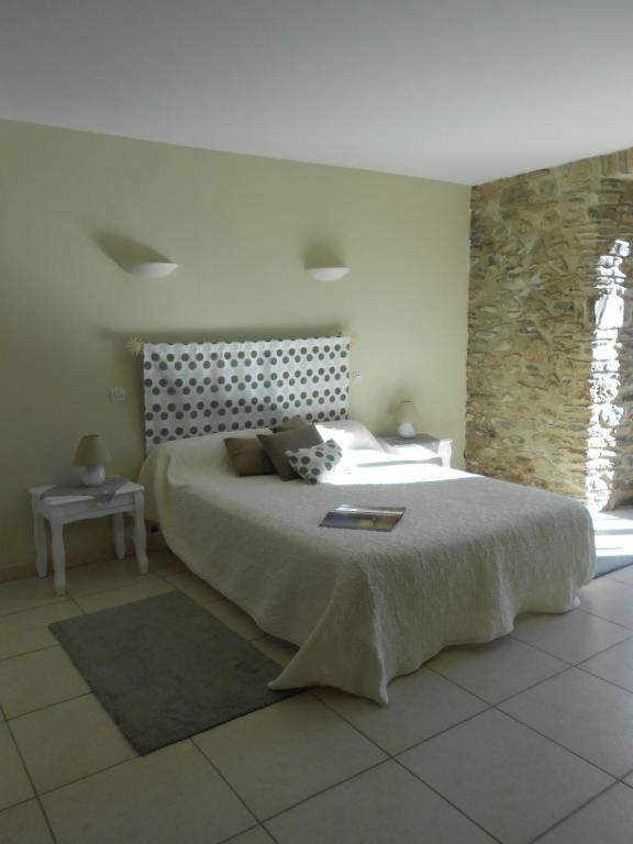 赛拉古斯Mas Rondole - Chambres d'hôtes的一间卧室设有一张大床和石墙