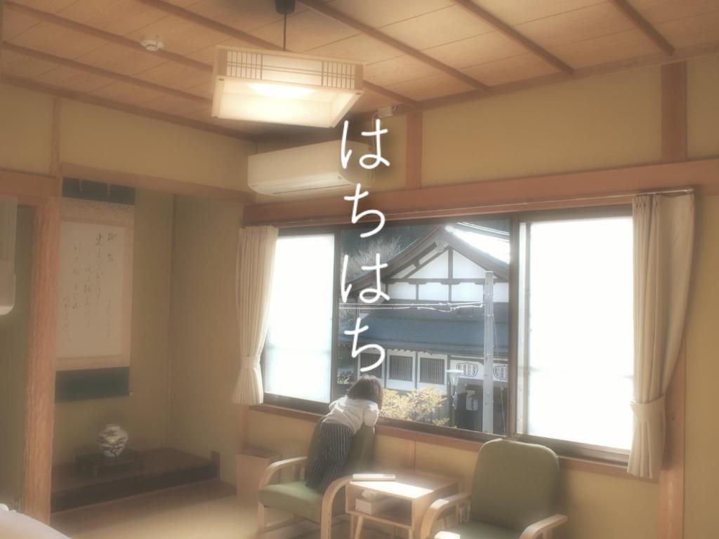 高野山Guest House hachi hachi的坐在椅子上,从窗户望出去的人