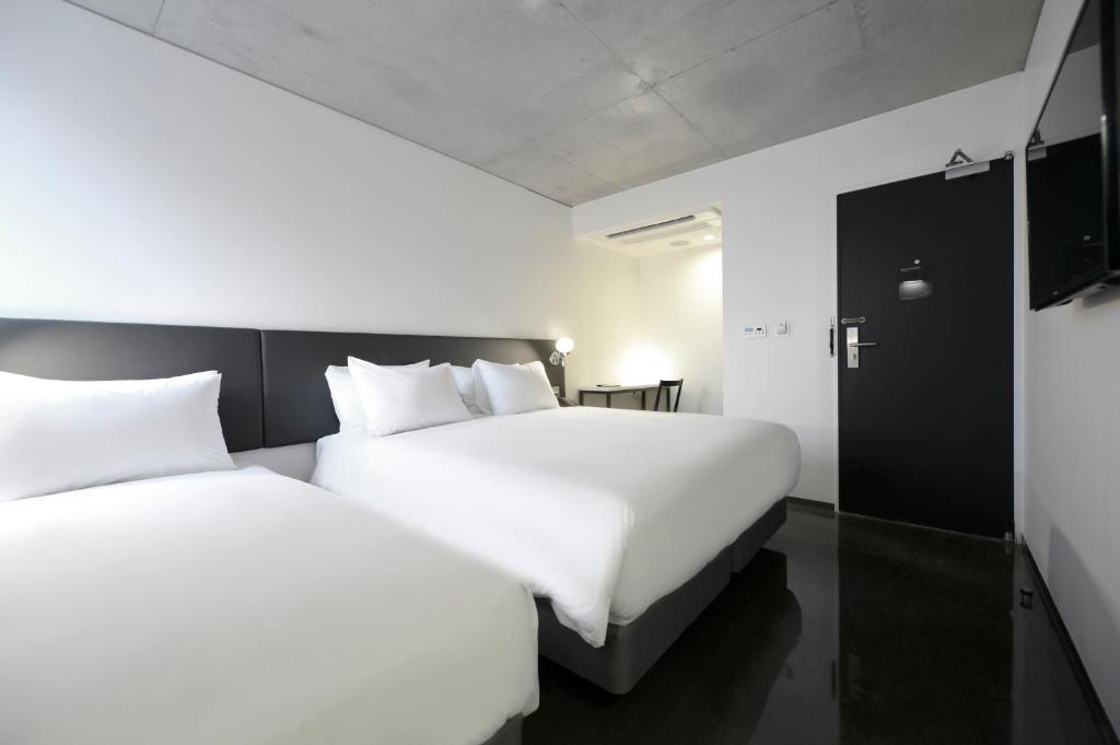 首尔明洞克莱托酒店的配有白色床单的酒店客房内的两张床