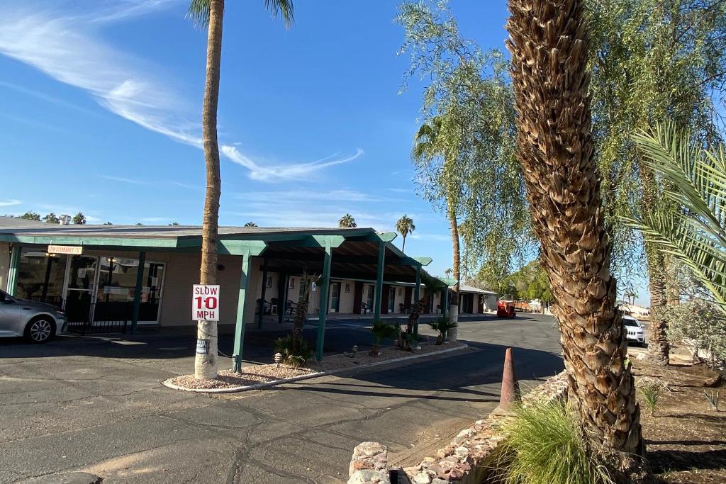 优马OYO Hotel Yuma AZ Desert Grove的街道前方有棕榈树的建筑