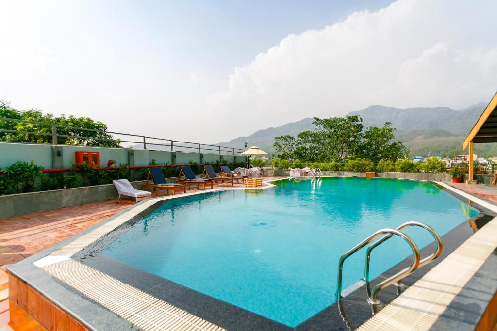 瑞诗凯诗Hotel Natraj Rishikesh的一座带椅子和山脉的大型游泳池