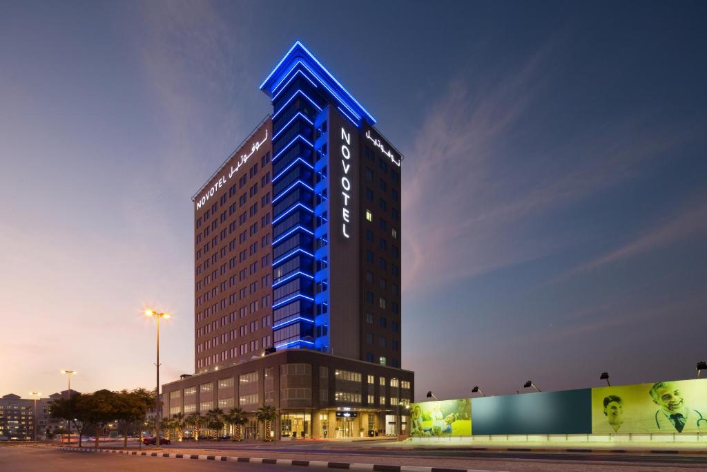 迪拜Novotel Bur Dubai - Healthcare City的上面有蓝色标志的高楼