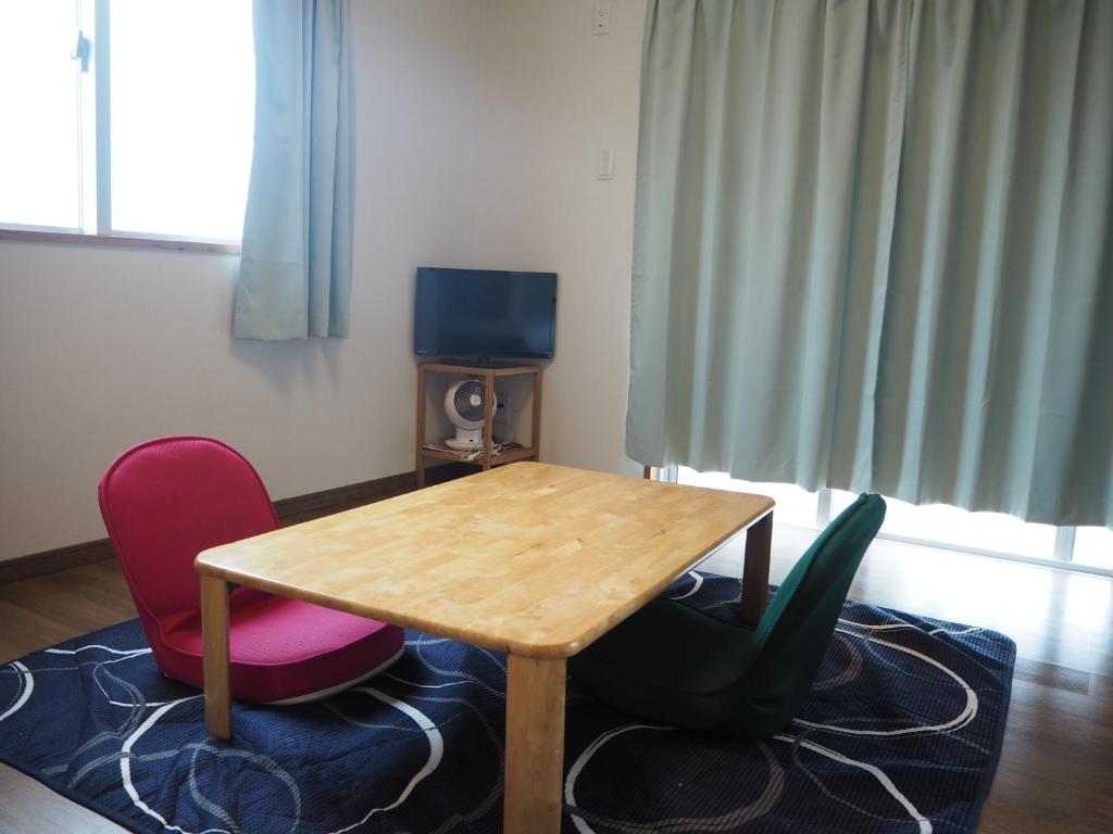 宫古岛Guesthouse Sea Turtle的配有木桌和两把椅子的房间