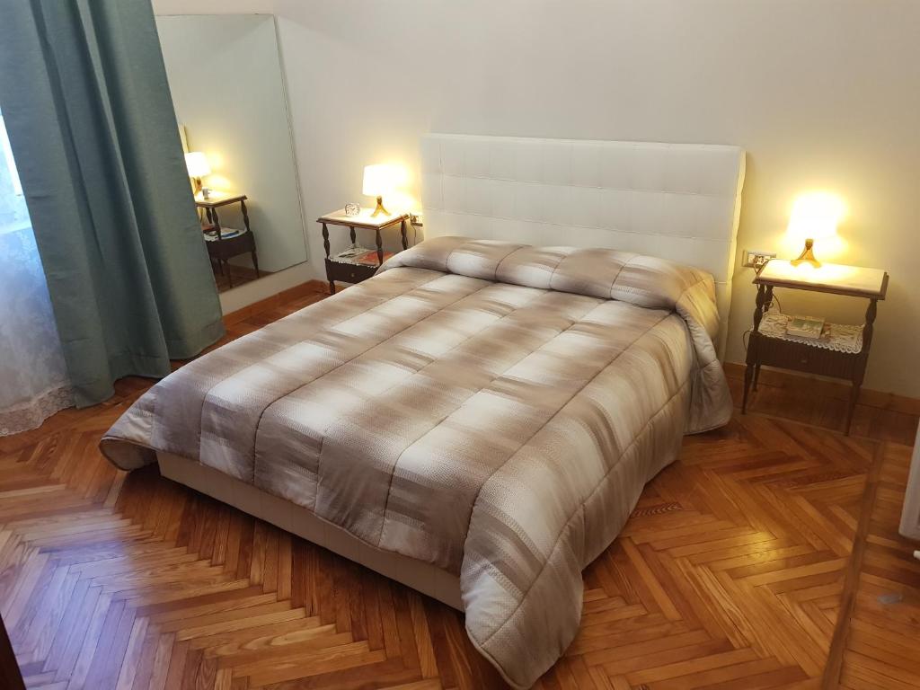 阿斯蒂Appartamento Rosalba的卧室内的一张床铺,两台台灯放在两张桌子上