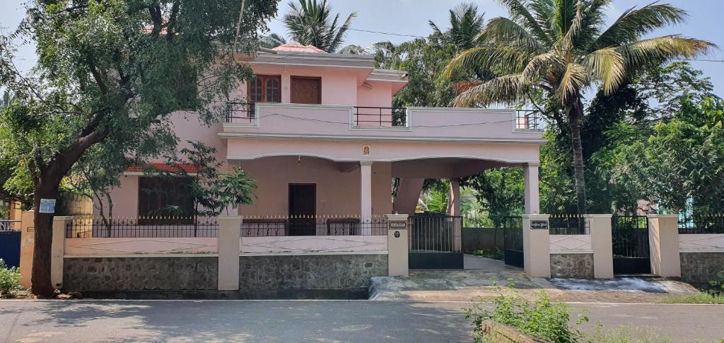 库塔兰Podhigai Garden Villa的粉红色的房子,在街上设有阳台