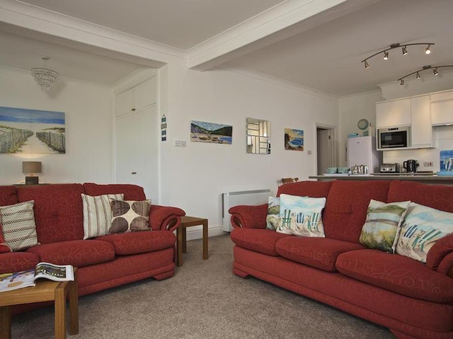 金斯布里奇Cove View的一间带两张红色沙发的客厅和一间厨房