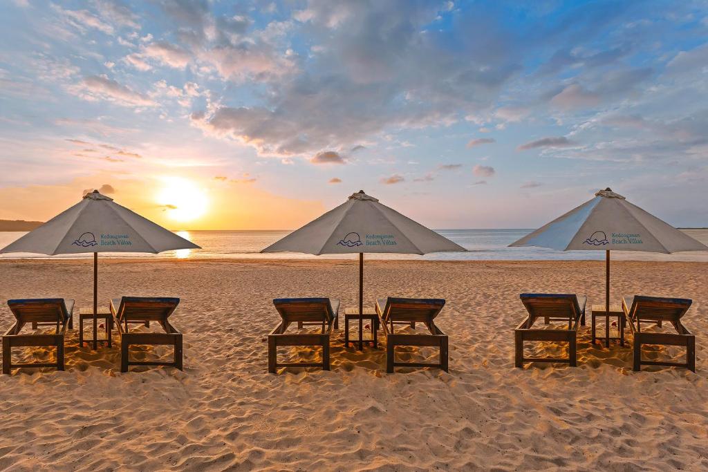 金巴兰Kedonganan Beach Villas的海滩上的一组椅子和遮阳伞