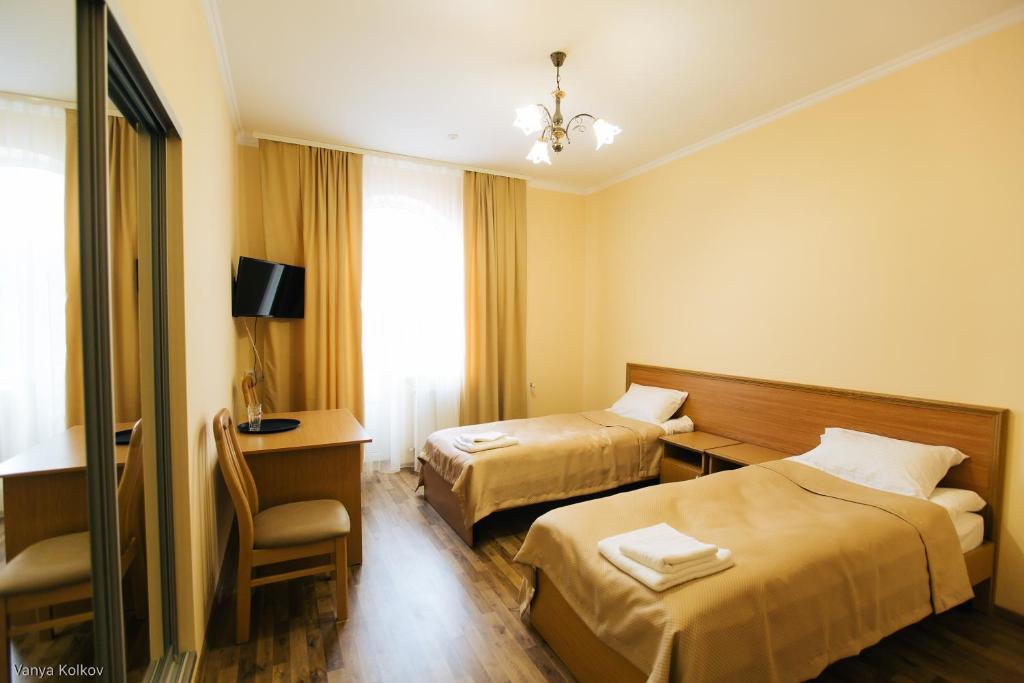 切尔诺夫策Готель Баронський Двір的酒店客房 - 带两张床、一张桌子和一把椅子