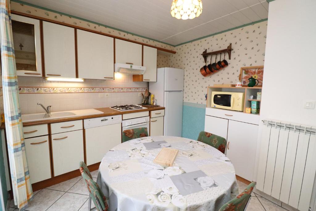 Mentièresla grange aux créations的一间带桌子的厨房和一间带白色橱柜的厨房
