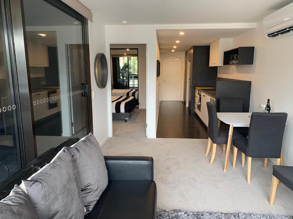 堪培拉Midnight Luxe 1 BR Executive Apartment L1 in the heart of Braddon Pool Sauna Secure Parking Wine WiFi的客厅以及带沙发和桌子的厨房。
