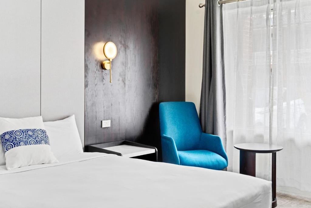 班克斯镇WM Bankstown的一间卧室配有一张床和一张蓝色椅子