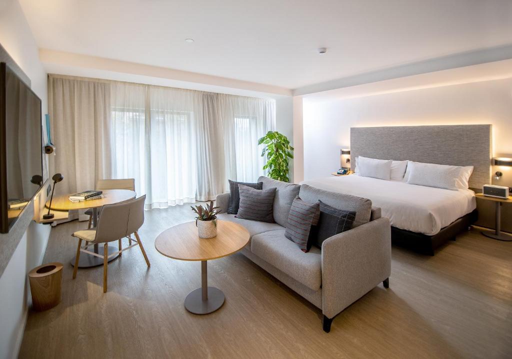 萨拉戈萨INNSiDE by Meliá Zaragoza的酒店客房配有床、沙发和桌子。