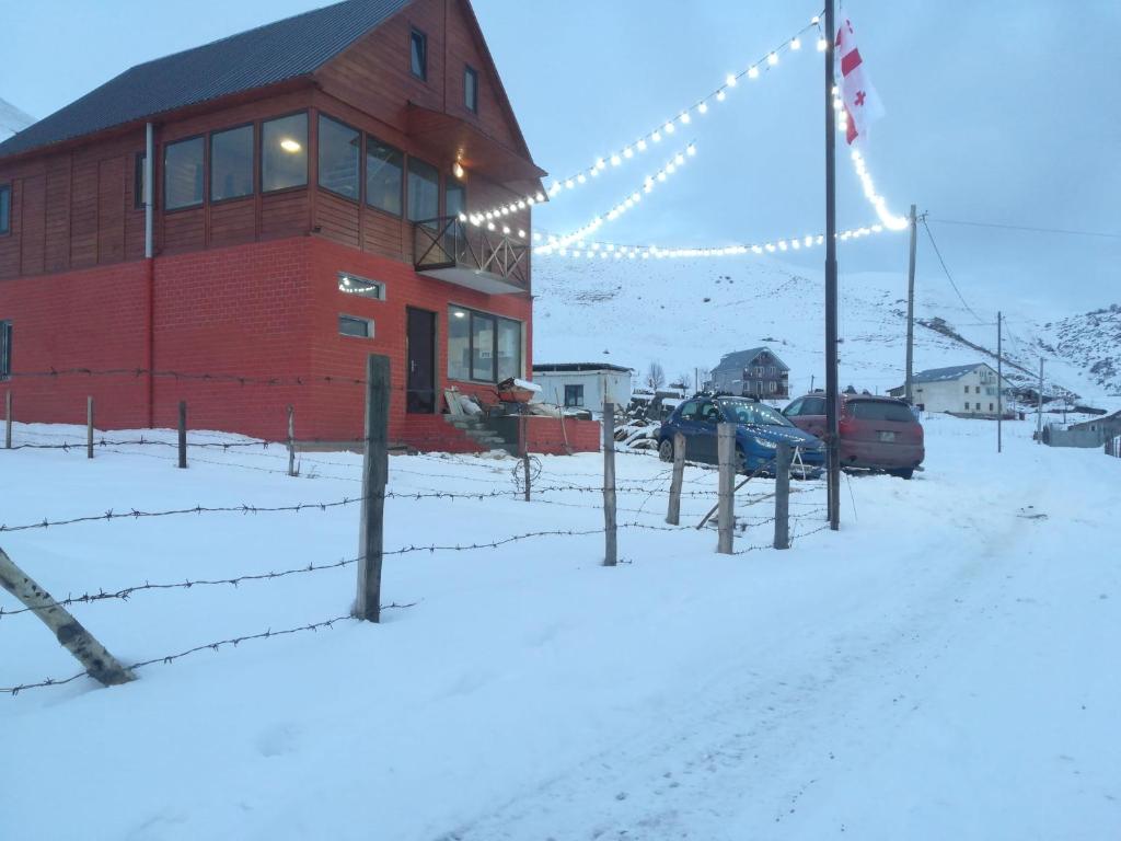 古多里family hotel Mtamta的雪中带栅栏的红色建筑