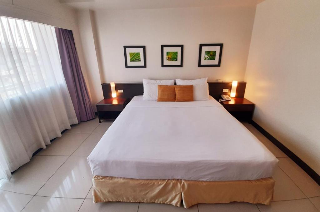 南芭堤雅格兰大酒店的卧室配有一张带两张桌子的大型白色床