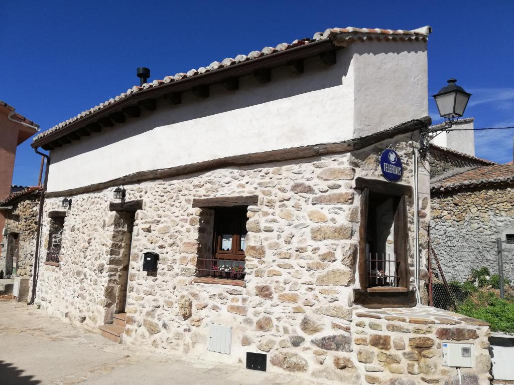 洛索亚河畔加尔甘蒂利亚La Casita de Teléfonos的一座带两扇窗户和街道的古老石头建筑