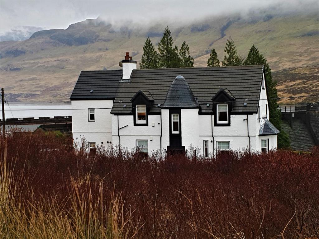 斯特灵Loch Arklet House的山前有黑色屋顶的白色房子