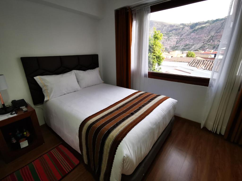 乌鲁班巴Hotel Andes de Urubamba的一间卧室设有一张大床和大窗户