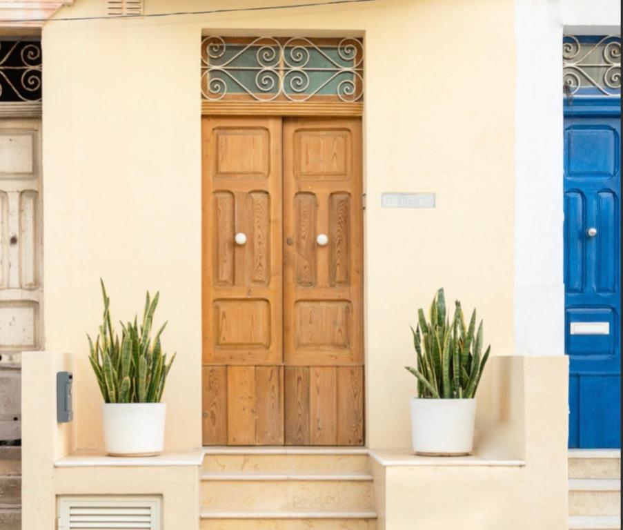 圣保罗湾城Summer House的木门,房子上装有两盆植物