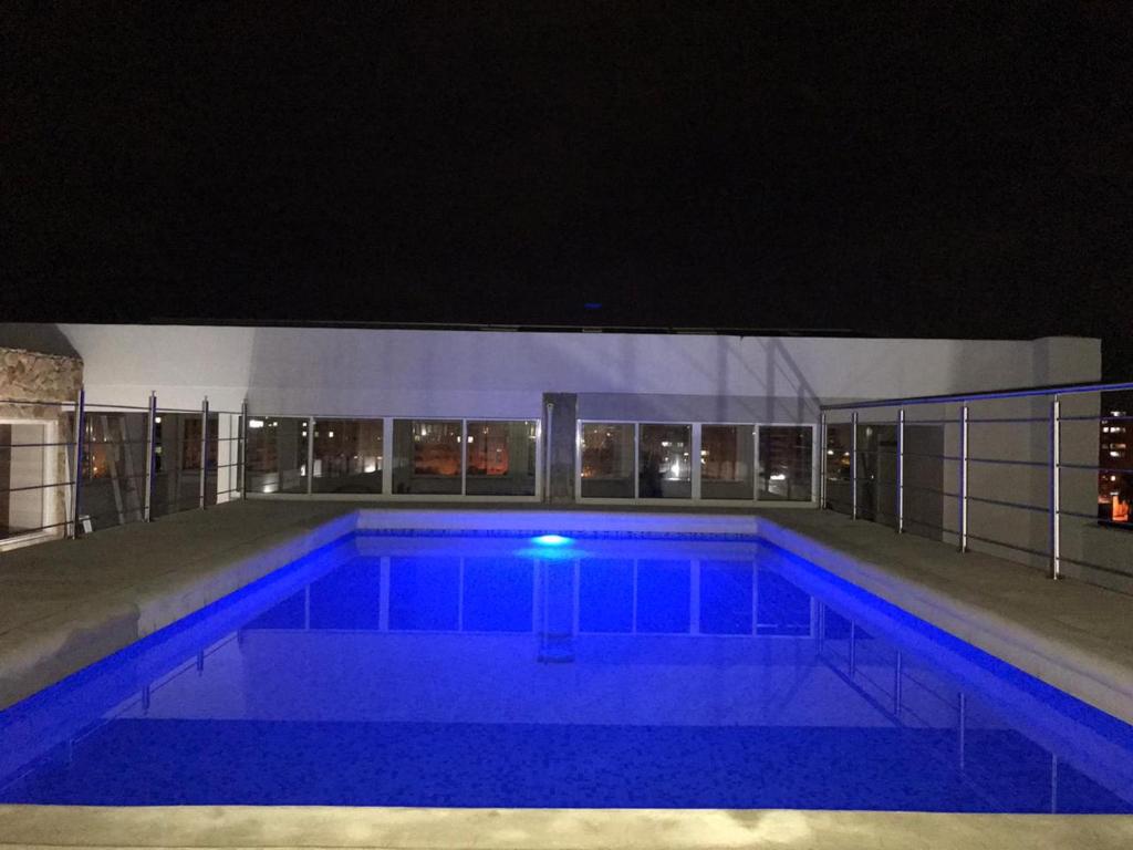 卡利Aparta Suites La Flora的夜间大型游泳池,灯光蓝色