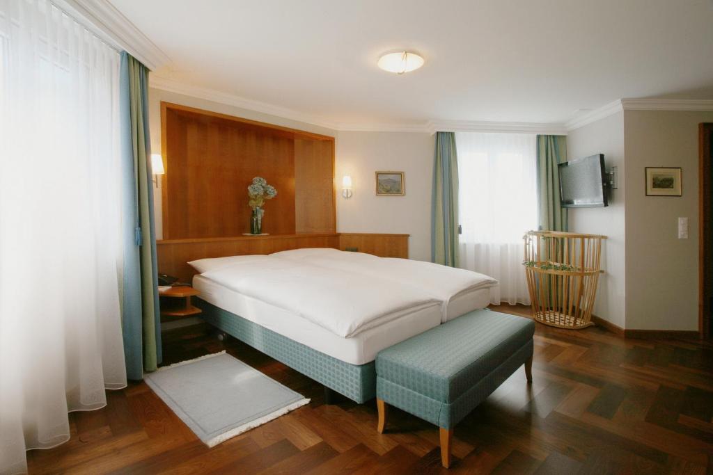 阿彭策尔赫克特阿彭策尔酒店的卧室配有白色大床和长凳