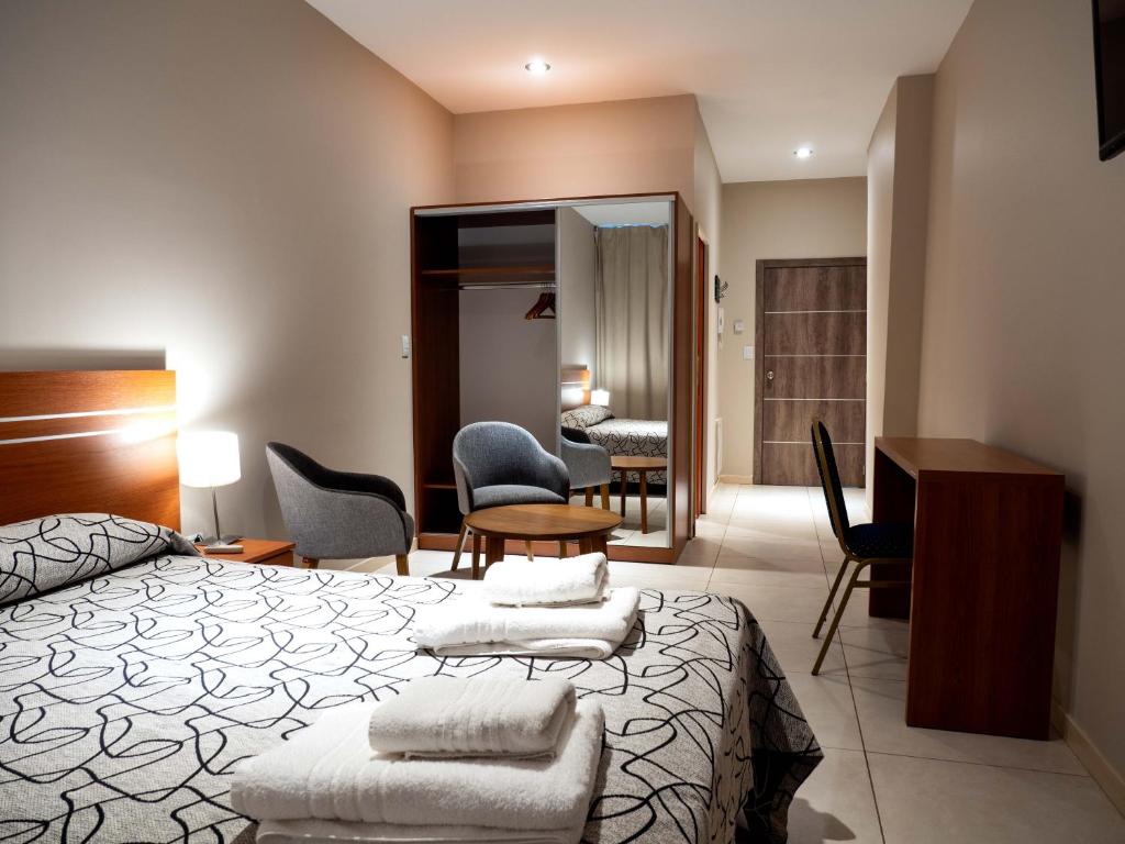 内乌肯LELOIR Suites & Meetings的卧室配有一张床、一张桌子和椅子