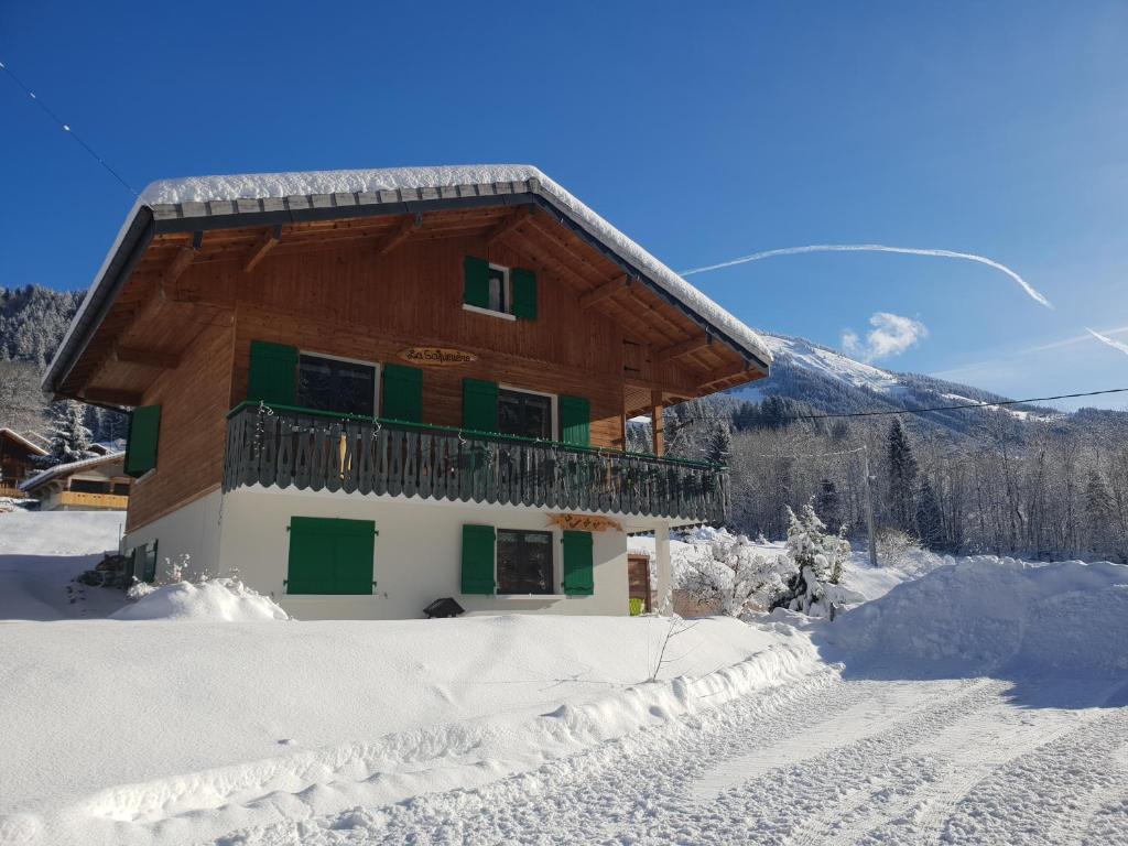 拉夏贝尔德邦达Chalet la sapiniere的雪中的房子,背景是山