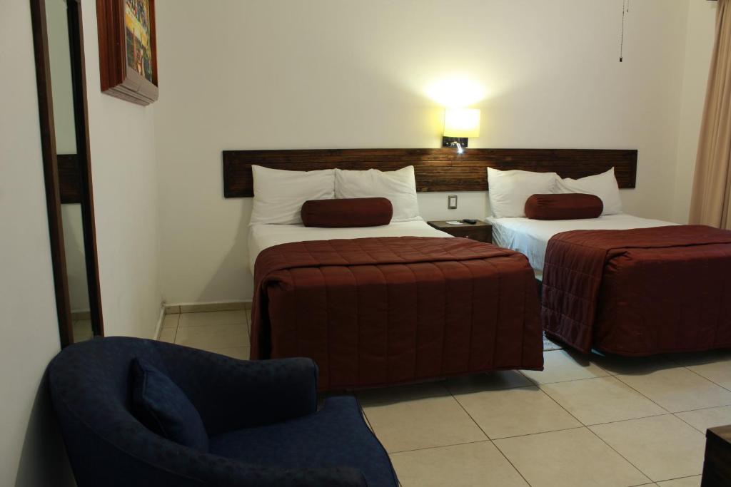 乌鲁阿潘HOTEL MI SOLAR EJECUTIVO的酒店客房,配有两张床和椅子