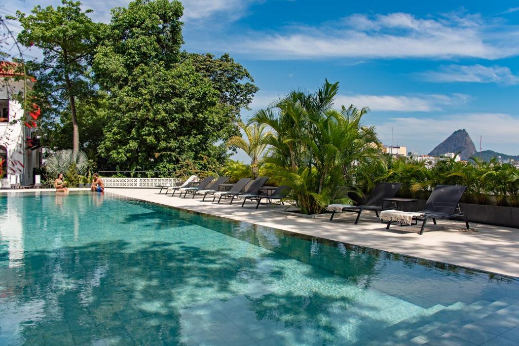 里约热内卢Villa Paranaguá Hotel & Spa - Boutique Hotel的一个带椅子的游泳池,后方是一座山。