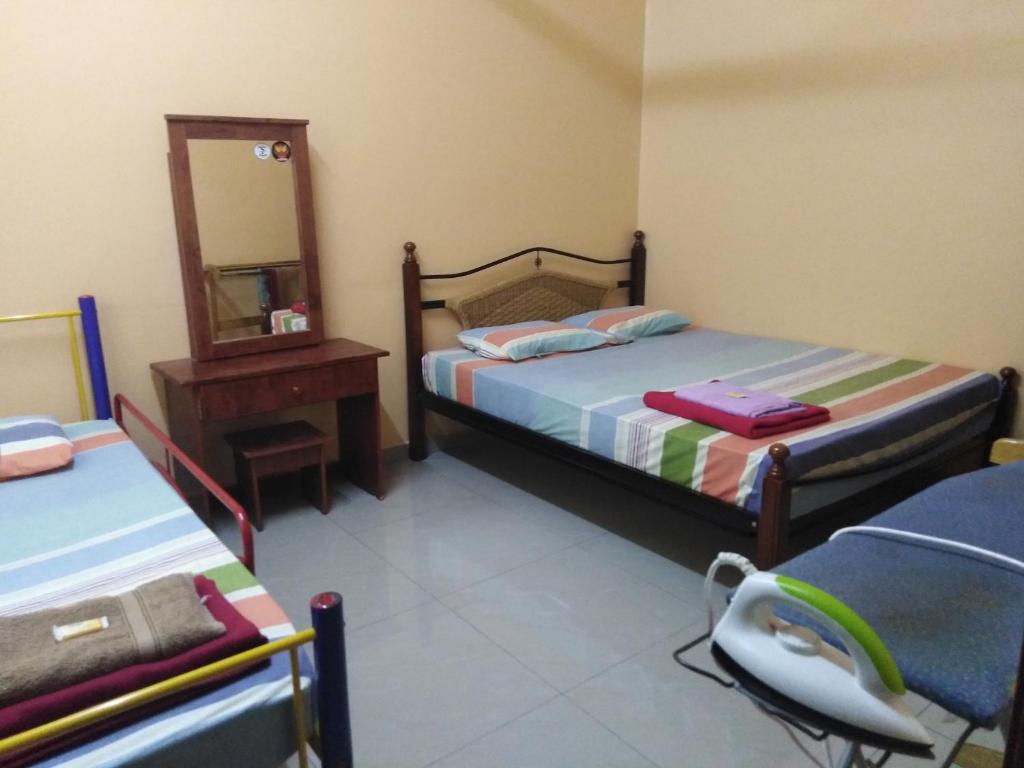 巴生Homestay Teratak Umi Klang的一间卧室配有两张床、镜子和椅子