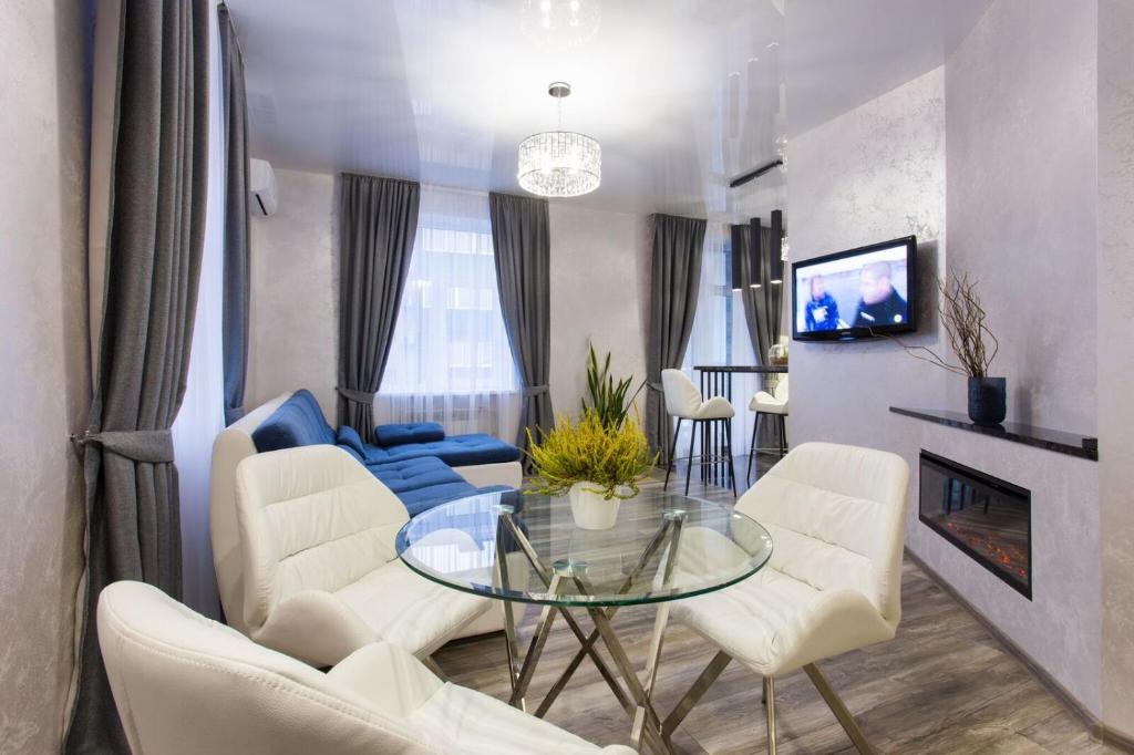 哈尔科夫New luxury Apartment in the Center on Konstitution Square的客厅配有玻璃桌和白色椅子