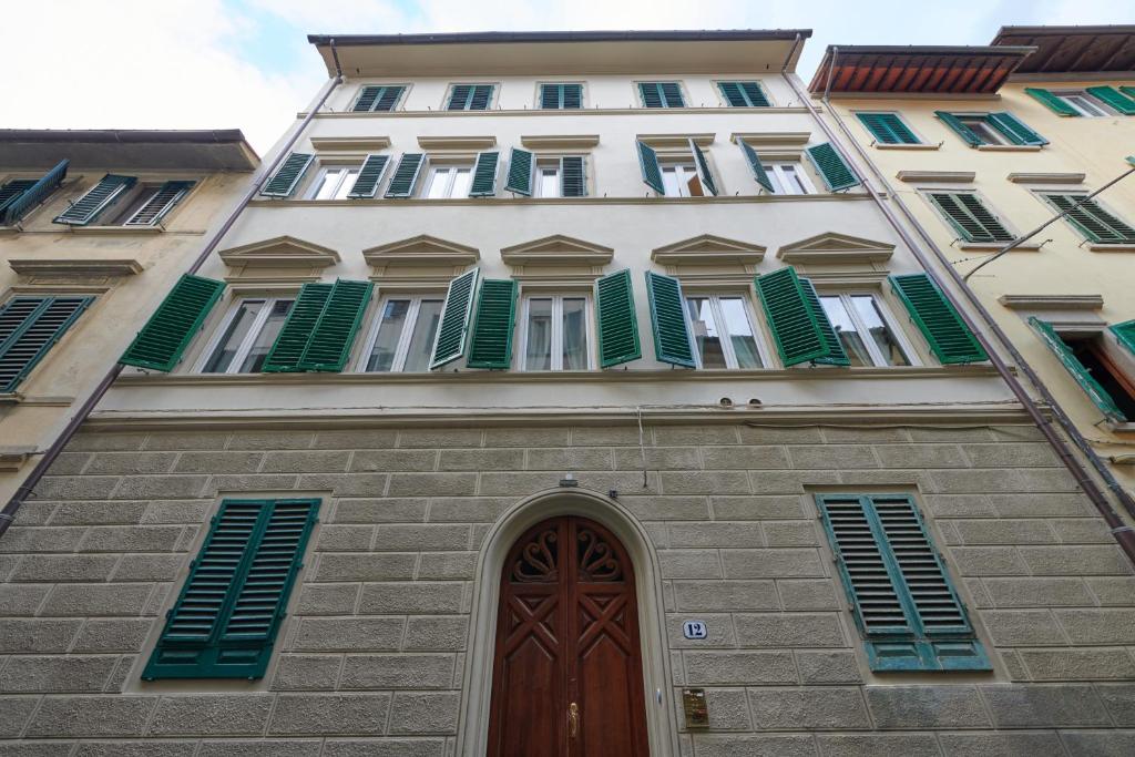 佛罗伦萨Florence&Us Santa Croce的一座高大的建筑,设有绿色百叶窗和门