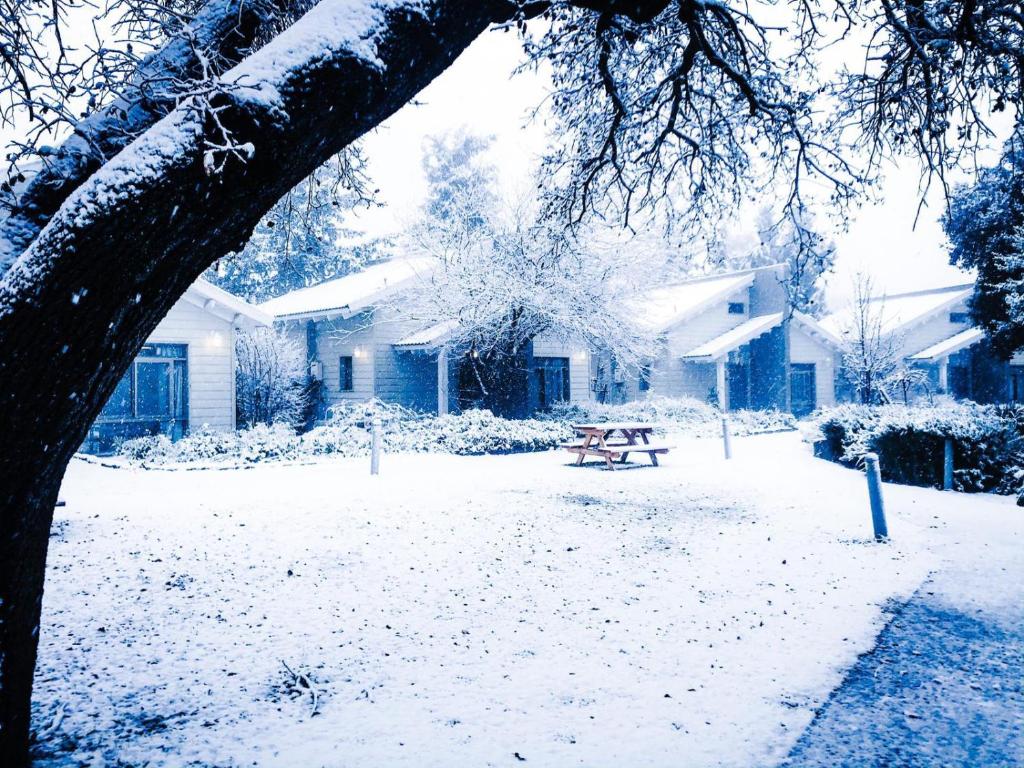 恩泽万Ein Zivan Village Resort的房屋前有雪盖的院子,配有野餐桌