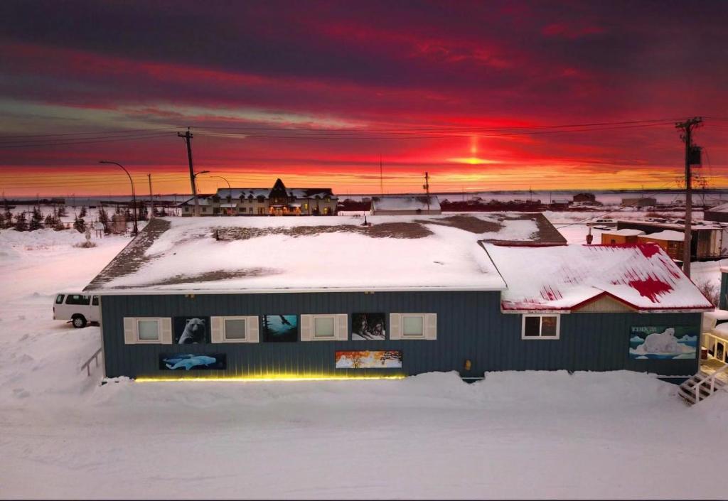 丘吉尔IceBerg Inn的雪覆盖的房子,背景是日落