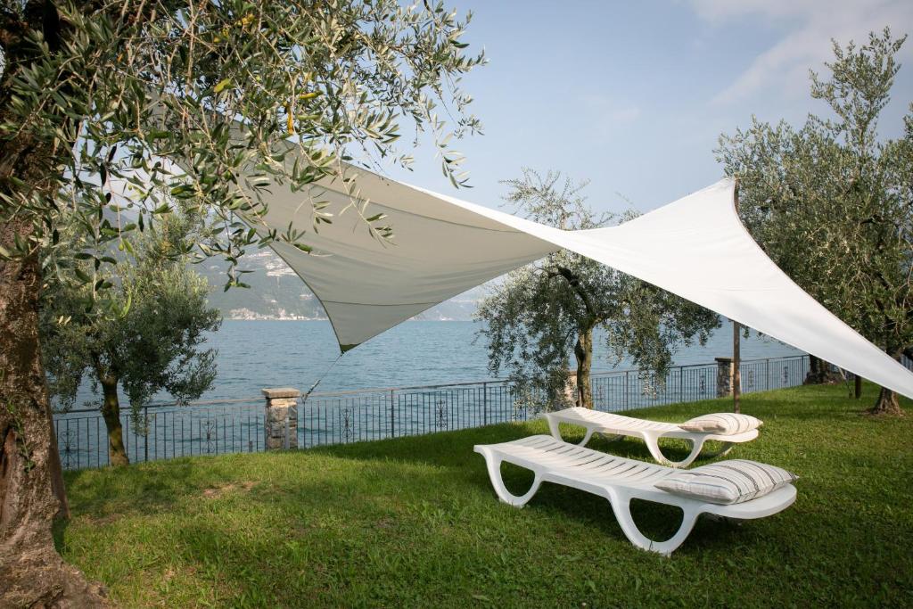蒙泰伊索拉IseoLakeRental - La Stallina - Monte Isola的两把椅子和一把白色的伞放在草地上