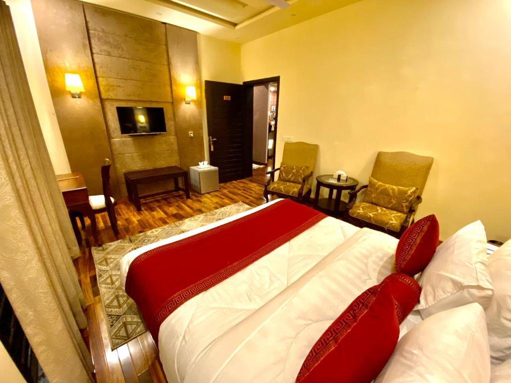 拉合尔Shelton’s Rezidor Lahore的一间卧室配有一张床、两把椅子和一张桌子