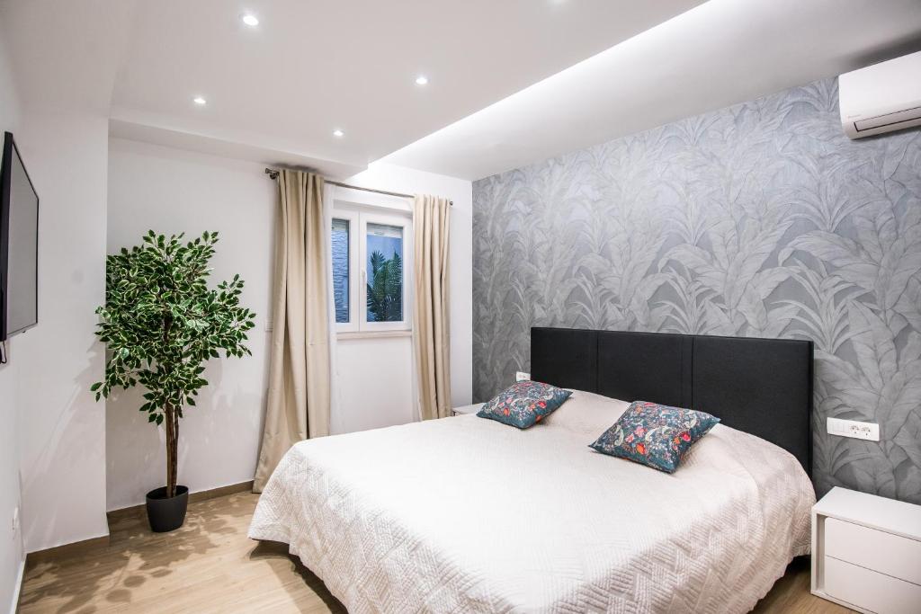 杜布罗夫尼克Dubrovnik Spectrum Rooms的一间卧室配有一张床和盆栽植物