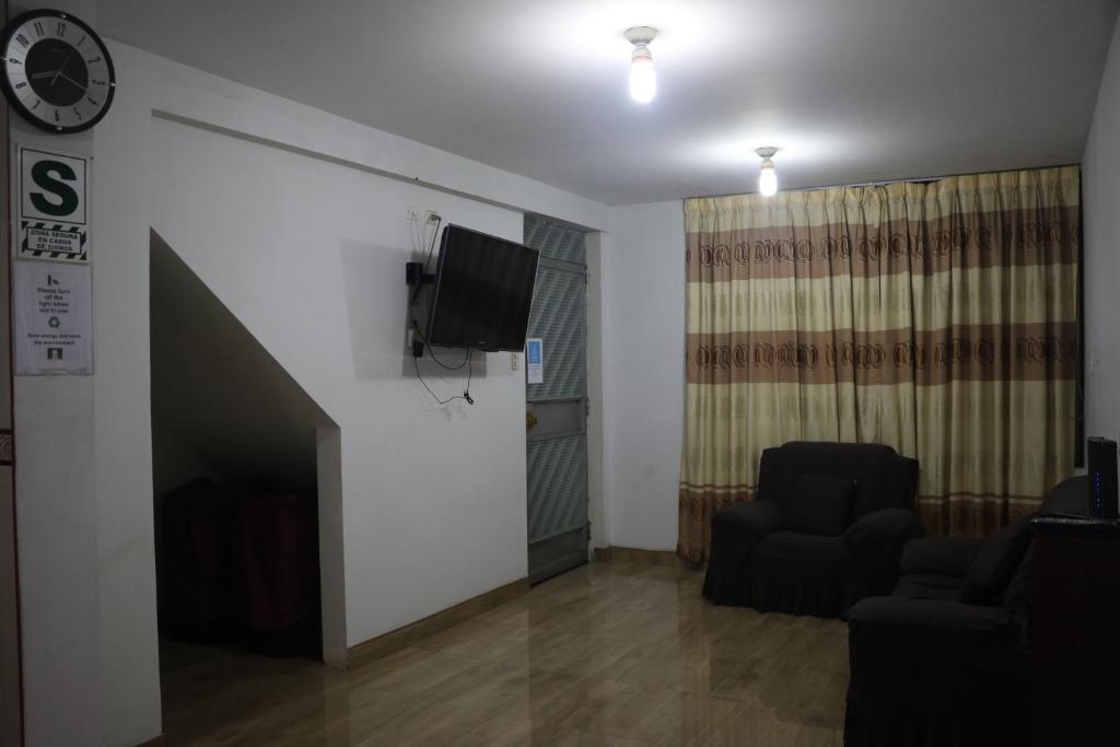 利马Wasi Airport Apartment的客厅配有两把椅子和墙上的电视