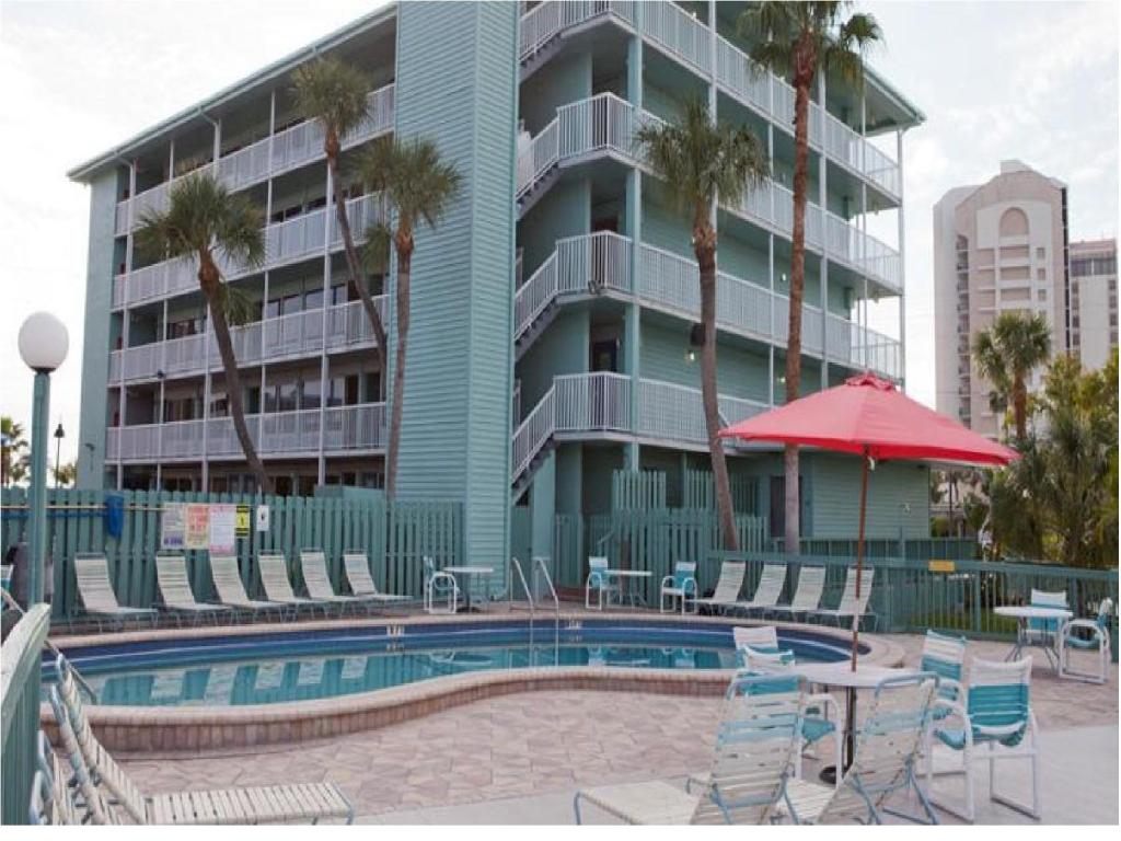 克利尔沃特Clearwater Beach Hotel的一座带椅子和遮阳伞的游泳池以及一座建筑