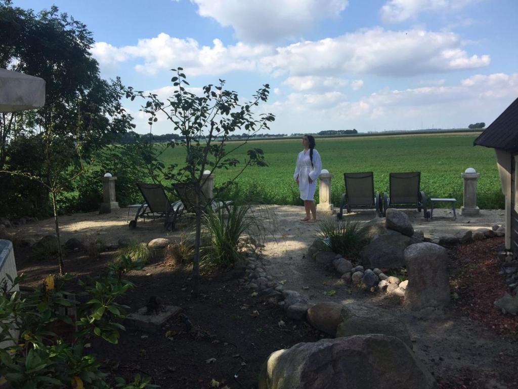 米德沃达Wellness Sauna Beauty Farm Midwolda的站在院子里的女人,有椅子和田野