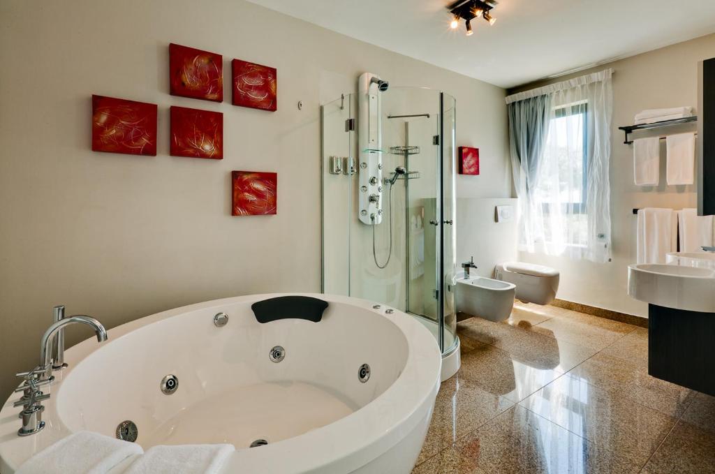 开普敦Camps Bay Ruby Suite的一间带大型白色浴缸和淋浴的浴室