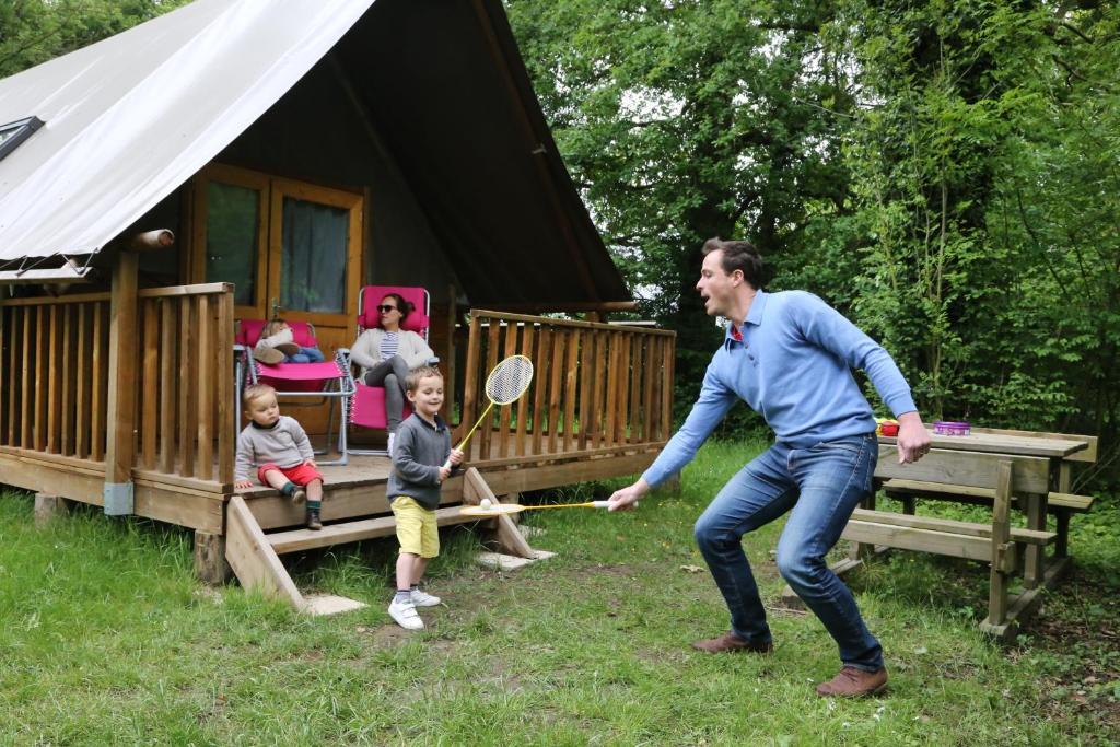 维拉尔雷东布Camping le Nid du Parc的一名男子和两名儿童玩网球拍