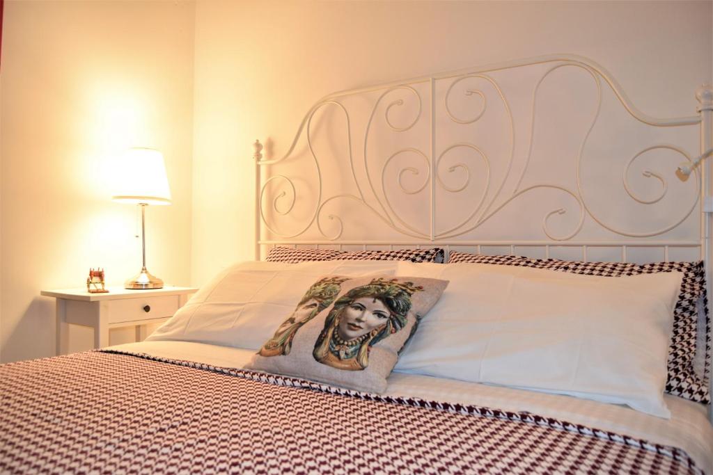 锡拉库扎IL MORO holiday home的一张带床头板的床铺,上面有一张女人的照片