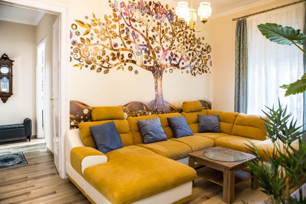 毛科Villa Apartman的客厅配有黄色沙发,墙上挂着一棵树