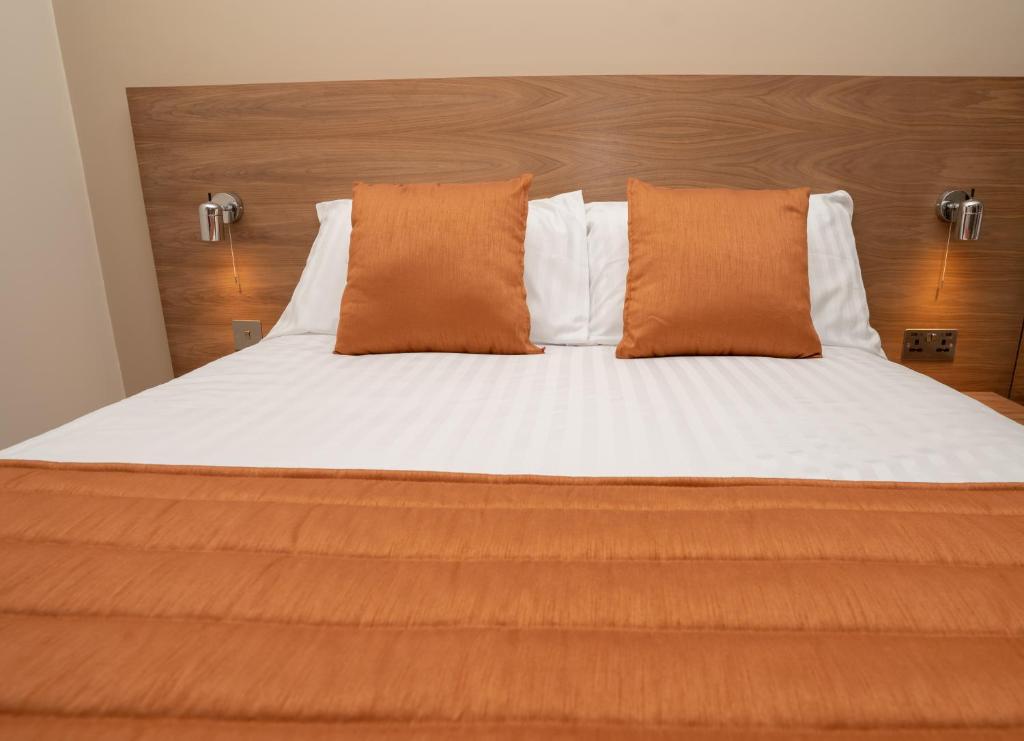 卢顿Eagle Hotel Luton Airport的一张配有橙色和白色床单及枕头的床