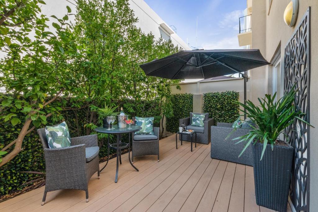 珀斯滨江半岛服务式公寓的庭院配有桌椅和遮阳伞。