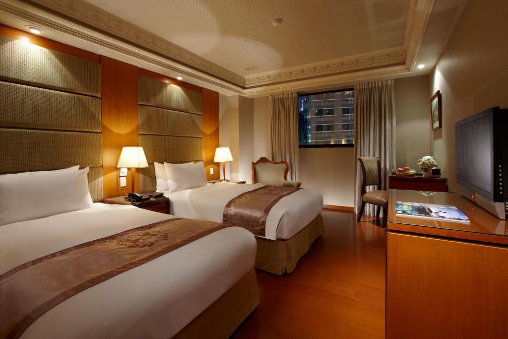 台北乔合大饭店的酒店客房设有两张床和一台平面电视。