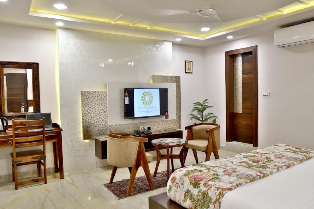 斋浦尔Marigold Inn- Homestay的酒店客房配有一张床、一张书桌和一台电视。