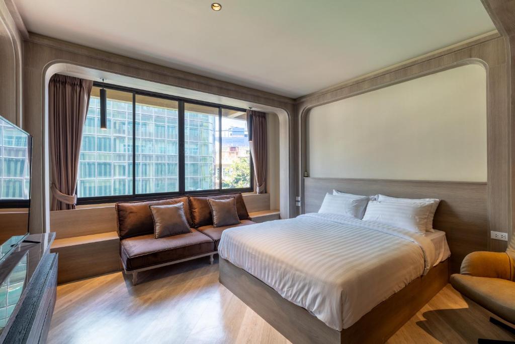 曼谷The Spades Private Residence的一间卧室配有一张床、一张沙发和一个窗口