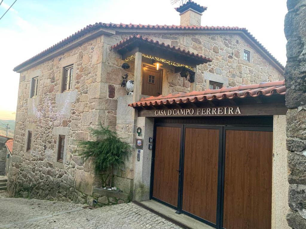 皮同伊斯-达斯-朱尼亚斯卡萨坎普费雷拉度假屋的一座石头建筑,设有大型木制车库门
